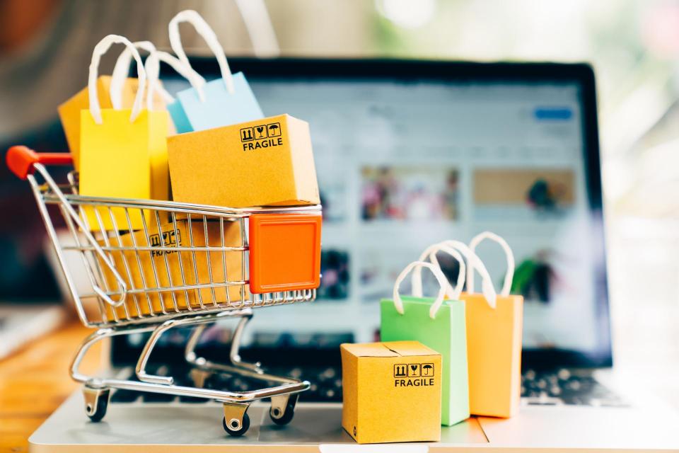 Image of small shopping cart filled with boxes in front of a computer